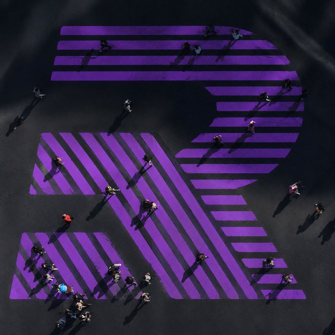 An aerial view of a purple-striped pedestrian crosswalk with people walking across it.