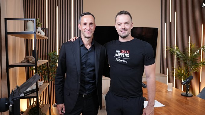Two men pose together in a modern studio setting, with one wearing a black t-shirt reading "BITWISE - WHEN [SHIFT] HAPPENS" and the other in a dark blazer. The image reflects the podcast collaboration between the Bitwise Bitcoin advocate and Scott Melker of "The Wolf Of All Streets."