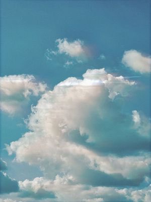 A serene photograph of a blue sky filled with large, fluffy white clouds.