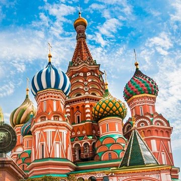 A vibrant photograph of St. Basil's Cathedral in Moscow, showcasing its colorful onion domes against a partly cloudy blue sky.