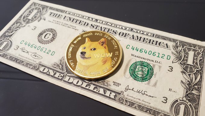 A gold Dogecoin cryptocurrency coin featuring the Shiba Inu dog and 'wow much coin how money' text rests on top of a US one-dollar bill.