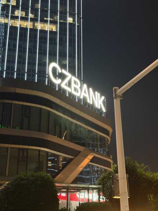 A nighttime photograph of the CZBANK building with illuminated signage on a modern high-rise structure.