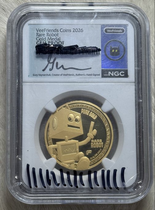 An NGC-graded VeeFriends Coins 2026 Rare Robot Gold Medal GEM PROOF coin in a protective slab, featuring a robot design and a signature from creator Gary Vaynerchuk.