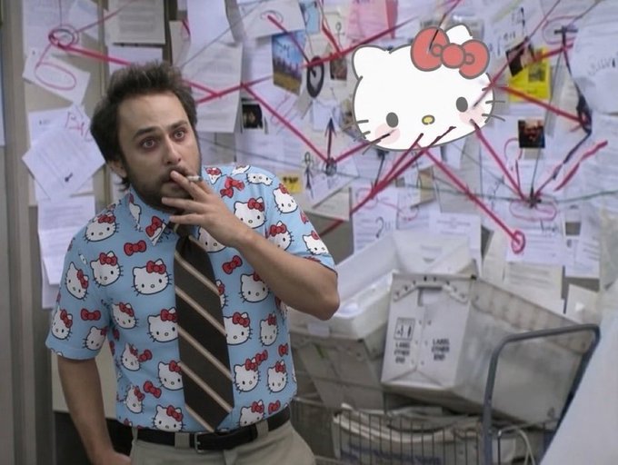 A man wearing a Hello Kitty shirt and tie smokes in front of a conspiracy board covered in papers and red string, with a Hello Kitty graphic in the upper right.