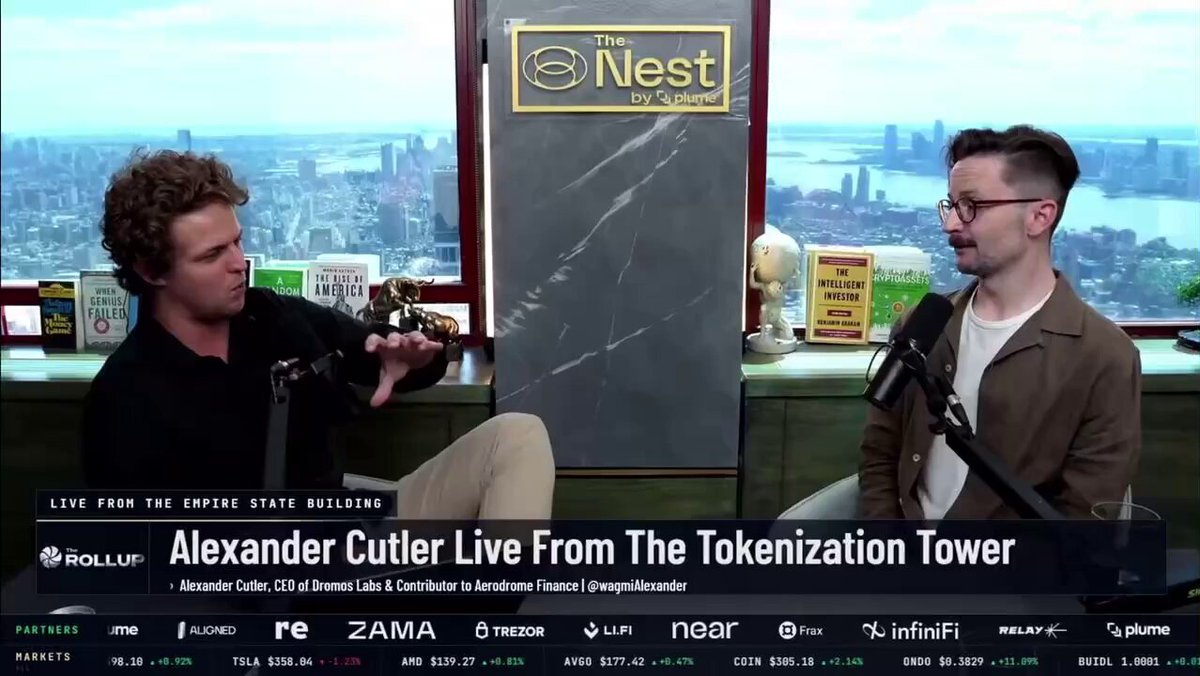 The image shows two men sitting next to each other at a desk with a microphone, likely recording an interview or podcast. The background features a city skyline, suggesting they are in a studio setting. The text "The Nest" appears multiple times on the image, indicating that this is related to a news program or discussion about cryptocurrency and predictions markets.