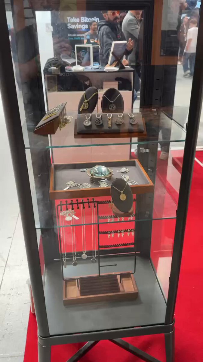 The image features a glass display case filled with various jewelry items, including necklaces and bracelets. The jewelry pieces are arranged neatly inside the case, showcasing their beauty and craftsmanship. In addition to the jewelry, there are also some books placed on top of the display case, possibly containing information about the jewelry or related topics. The background suggests that this exhibit is taking place at a fair or market where people can come and explore the different items for sale.

The post in question seems to be promoting an event or booth dedicated to selling Bitcoin coins, as indicated by the text "Definitely check out the awesome treasures in the case @BULLBITCOIN_ booth @BTCPrague". The focus of this particular post is on the jewelry and books displayed within the glass case.