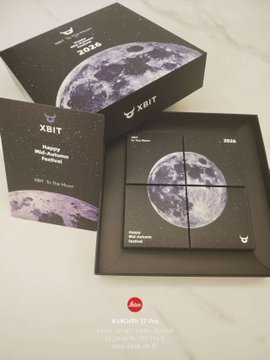 A promotional image for XBIT, featuring black boxes and product packaging decorated with purple moon graphics and text like 'XBIT', 'Happy White Moon Festival', and 'Tết Đến Rồi'.