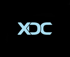 The image features the "XDC" logo in light blue text on a black background, representing the XinFin XDC Network cryptocurrency. The clean, minimalist branding aligns with the post's message of XDC being "part of our world," symbolizing its presence and role in the global digital economy.