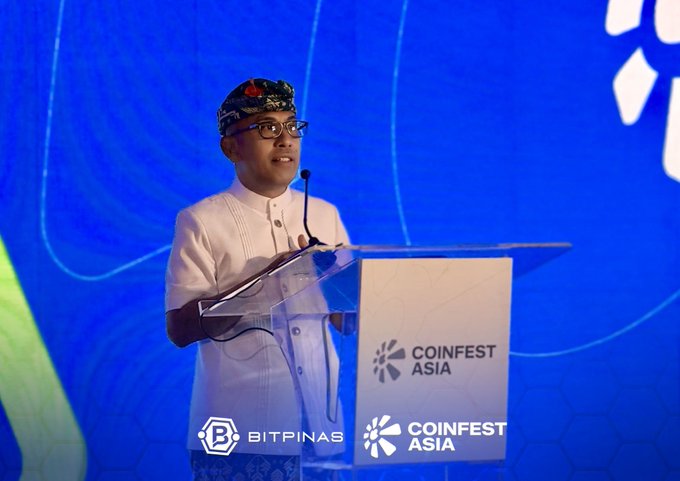 A man wearing glasses and a traditional Indonesian udeng headpiece speaks at a podium displaying the 'COINFEST ASIA' logo, with a 'BITPINAS' watermark in the corner.