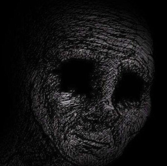 A dark, haunting portrait of a skull-like face with deeply textured, wrinkled skin and hollow black eye sockets fading into a black background.