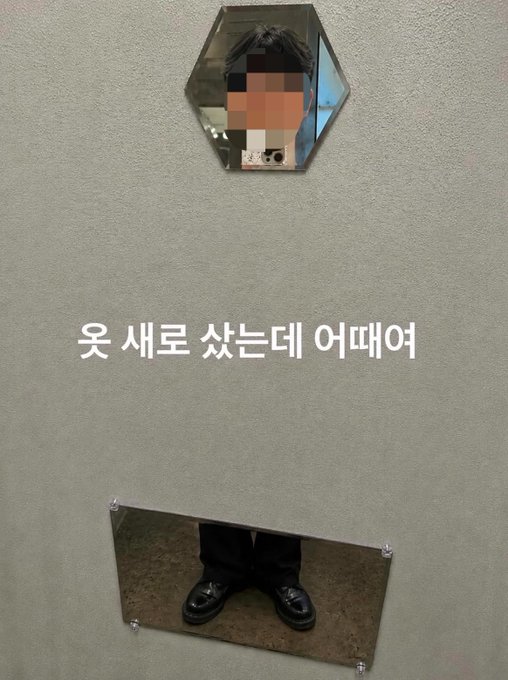 An art installation featuring a hexagonal mirror reflecting a person's face (pixelated) above a rectangular mirror showing only their black shoes, with Korean text '웃 새로 샀는데 어때어' meaning 'How's my new mirror I bought?'