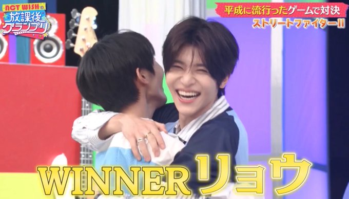 The image shows two young men sharing a joyful hug on what appears to be a Japanese variety TV show, with the smiling winner on the right being congratulated by his opponent. On-screen Japanese text reads "平成に流行ったゲームで対決" (Showdown with games that were popular in the Heisei era) and "ストリートファイターII" (Street Fighter II) in the upper right, along with "HOT WISH 放課後グランプリ" (Hot Wish After School Grand Prix) in the upper left, while bold yellow text at the bottom declares "WINNER リョウ" (Winner Ryo), confirming the post's caption that Ryo emerged victorious in the gaming competition.