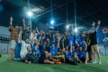 The image shows a group of men posing together, celebrating their victory with high fives and raised arms. They appear to be members of a soccer team who have just won a game or competition. The photo captures the excitement and camaraderie among the players as they celebrate their achievement on the field.