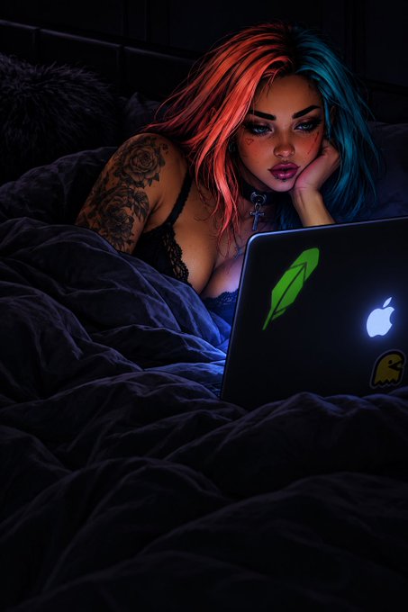 A digital illustration shows a woman with split-dyed red and blue hair and arm tattoos lying in bed, illuminated by the glow of a laptop displaying a green quill sticker and an Apple logo.