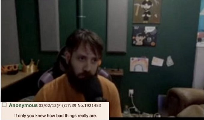 A bearded man in an orange shirt stares into a camera in a dimly lit room with wall art, captioned by "Anonymous 03/02/12(Fri)17:39 No. 1921453" saying "If only you knew how bad things really are," which lends a somber, ominous tone echoing the poster's feelings of exclusion and stagnation surrounding both COVID-era restrictions and frozen Bitcoin transactions.
