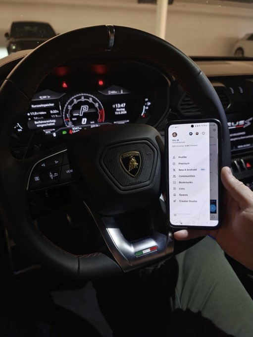 The image shows a person holding up their phone, which displays an app called "OG Memecoin" or "Lamborghini", possibly for sale. The car's interior features a Lamborghini logo, indicating that the vehicle might be associated with the brand. The person is likely considering purchasing this car and using it to showcase the app on social media platforms.