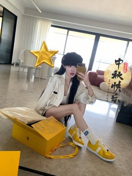 A woman taking a mirror selfie while sitting next to an open yellow box, wearing a white top and yellow high-top sneakers, with Chinese characters '中秋快乐' (Happy Mid-Autumn) overlaid on the image.