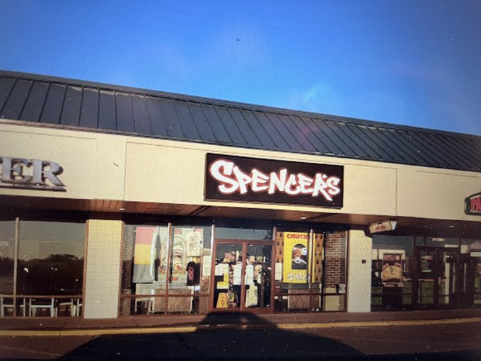 An exterior photograph of a strip mall storefront featuring a "SPENCERS" sign, with another partial sign reading "ER" visible on the left.
