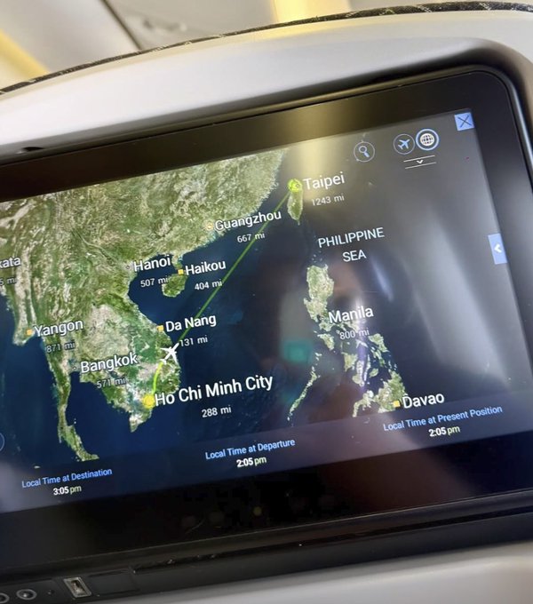 An airplane's seatback flight map displays the route from Taipei to Ho Chi Minh City with various Asian cities marked (Guangzhou 667mi, Hanoi 507mi, Da Nang 131mi, Bangkok 571mi) and local times showing 2:05pm departure and 3:05pm destination time. The image appears unrelated to the post about NVIDIA on Solana, though the airplane screen content doesn't connect to the cryptocurrency reference.