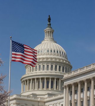 The U.S. Capitol dome stands tall beside a waving American flag, symbolizing the congressional deliberations ahead. This image reflects the political setting where the Clarity Act's fate will be decided, as senators and White House officials work to finalize crypto ethics rules before a critical Thursday vote.