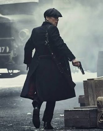A man in a long black coat and flat cap walks away through smoke, holding a pistol, with a vintage vehicle bearing "17" visible behind him. The gritty, dramatic scene echoes the post's theme of market turmoil, visually reinforcing the tension surrounding Bitcoin's $2.1T loss and the broader uncertainty in crypto and financial markets.