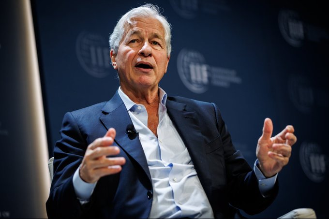 Jamie Dimon, CEO of JPMorgan Chase, speaks at an IIF (Institute of International Finance) event, gesturing with both hands as he discusses his warning about the U.S. potentially losing its reserve-currency status within 25 years—a concern that aligns with the post's call to watch gold, Bitcoin, and other scarce assets as hedges against eroding dollar dominance.