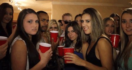 A group of young people at a party holding red plastic Solo cups, posing for the camera.