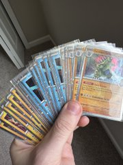 A hand holding a fan of various Pokémon trading cards.