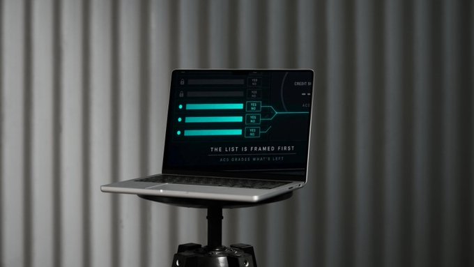 A laptop on a black stand displays a dark-themed interface with turquoise progress bars and the text 'THE LIST IS FRAMED FIRST' and '4C4 GRADISE WHAT'S LEFT,' set against a backdrop of grey curtains.