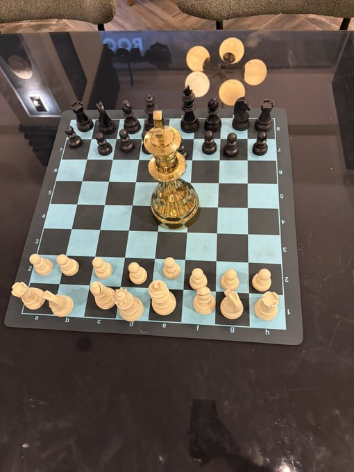 A glass chessboard is set up on a dark table with white pieces arranged at the bottom and black pieces at the top, featuring a large golden king piece prominently placed in the center of the board. The image plays on the metaphor of "making moves" in both chess and cryptocurrency, with the golden king symbolizing a strategic, decisive crypto play aimed at the "gm crypto twitter" audience.