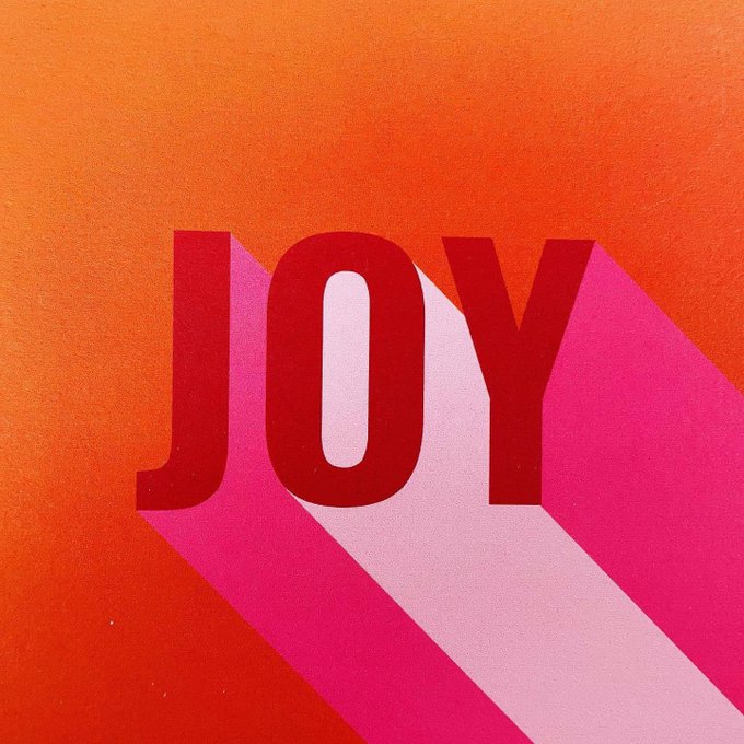 Minimalist poster design featuring the word 'JOY' in bold red letters casting a pink shadow on a bright orange textured background.