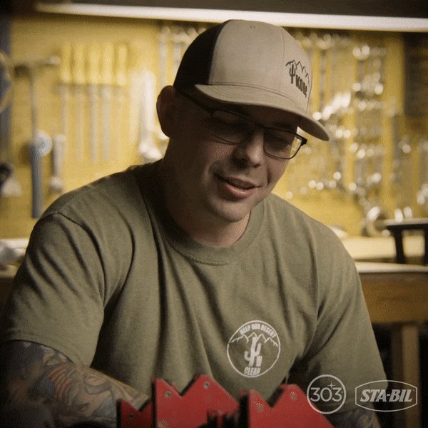 The image features a man wearing glasses and a tan baseball cap sitting at a workbench with various tools around him. The text in the image reads "RWA brings institutional money. Builders create products. Creators drive distribution. Together, they'r an economic engine." This suggests that the man is likely involved in some form of construction or woodworking project and is discussing the importance of RWA (Repair-Warranty-Addition) as a means to support his work.