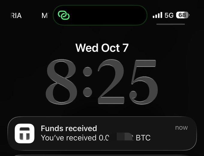 A smartphone lock screen at 8:25 on Wed Oct 7 shows a notification from a crypto wallet app stating "Funds received - You've received 0.0… BTC," matching the post about receiving a Bitcoin payment directly into a Tangem wallet.