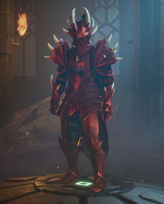 A character in red and black spiked armor standing in a dimly lit stone hall with a torch.