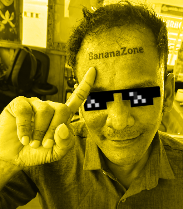The image depicts an individual wearing glasses with a banana tattooed on their forehead. They are holding up one finger, possibly pointing at something or making a gesture of approval. The background appears to be a public area, but no text can be seen in the photo. In addition to the person and their action, there is also some text that seems related to an event involving cryptocurrency, which suggests that this tattooed individual might have been involved in a project or discussion about Bitcoin or other crypto projects.