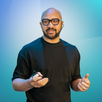 A bald man with glasses and a beard, wearing a black t-shirt, gestures with his hands while speaking, seemingly captured mid-presentation. The image accompanies a breaking news quote from Mysten Labs co-founder Adeniyi Abiodun, who appears to be the speaker pictured, discussing Sui's roadmap for late 2026 and 2027.