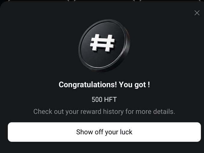 The image shows a popup notification from an app displaying a "Congratulations!" message for receiving 500 HFT tokens, featuring a black coin with a hashtag-like symbol. A button at the bottom invites the user to "Show off your luck," while text suggests checking reward history for more details. This directly illustrates the user's experience of winning 500 HFT (worth around 4 USDT) from the "Bull or Bear? Catch the BTC Wave" event by Bitget, as mentioned in the accompanying post.