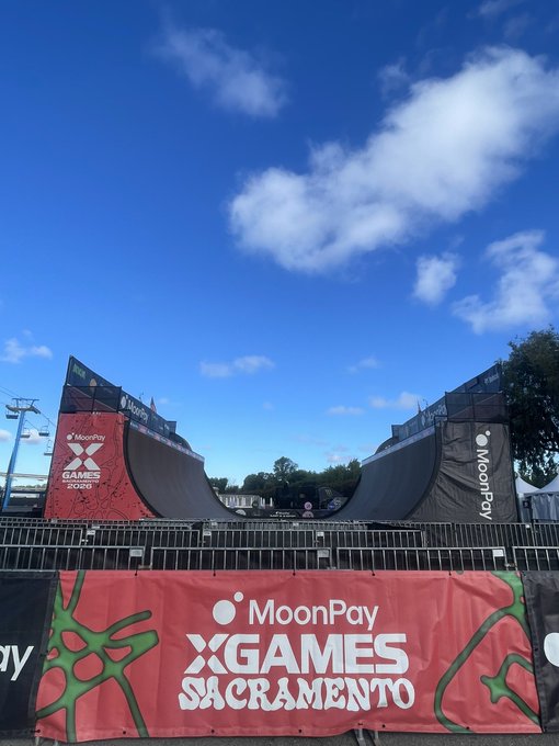 A massive halfpipe ramp dominates the scene under a bright blue sky, branded with "MoonPay" logos and a red banner reading "MoonPay X GAMES SACRAMENTO" with "2025" displayed on the left support pillar—showcasing MoonPay's prominent sponsorship of the X Games event.