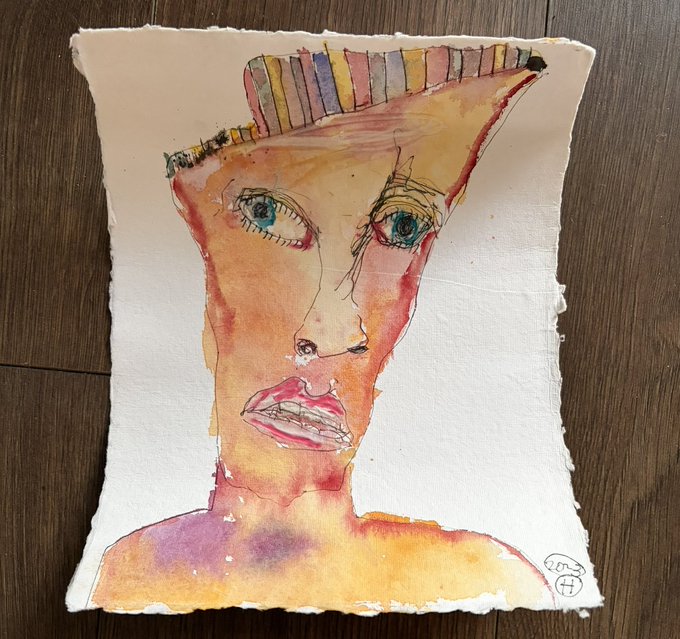 A watercolor and ink portrait painting of a stylized face with large expressive eyes, red lips, and a striped headpiece, displayed on a wooden surface.