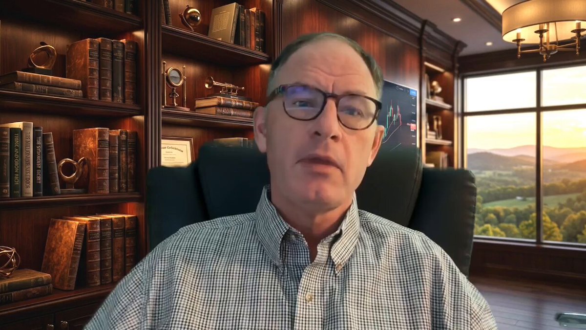 A man wearing glasses sits behind a desk with bookshelves filled with books around him, looking at the camera. A window can be seen in front of him, providing natural light for his workspace. The caption reads "The XRP Shift Is Coming Watch The Full Youtube Video Here: youtu.be/zuTZyWEQ9TY".