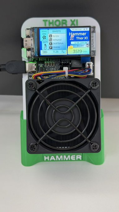 A green and white Hammer Thor XI device featuring a digital display showing voltage, current, power, and resistance readings, with a large cooling fan on the front.