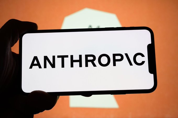 A hand holds a smartphone displaying the word "ANTHROPIC" in bold black letters against a white background.