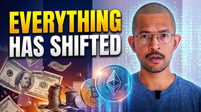 A man wearing glasses and a blue shirt speaks directly to the camera next to bold yellow text reading "EVERYTHING HAS SHIFTED," with imagery of U.S. dollar bills, stacks of coins, and Bitcoin and Ethereum cryptocurrency logos—visually emphasizing the video's urgent message about a critical turning point for crypto investors.