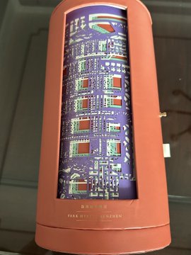 A close-up of a cylindrical orange object, possibly a lamp or decorative piece, featuring a cutout that reveals an intricate purple circuit board design with the 'SAMSUNG' logo at the top.