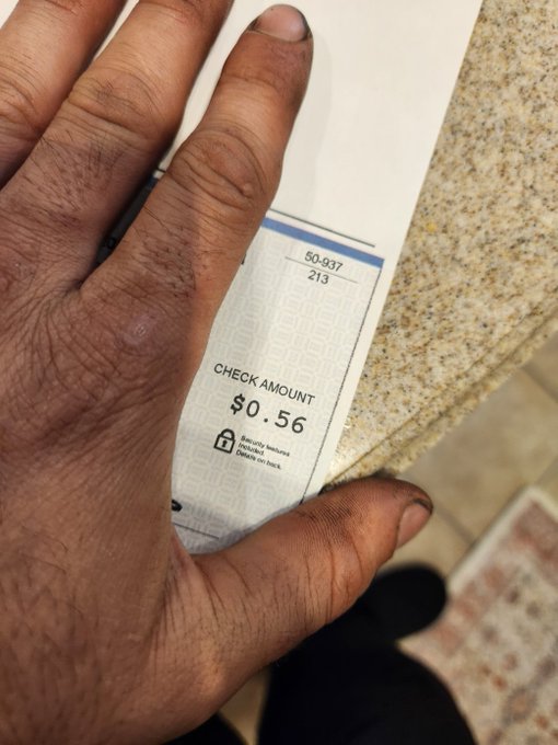A close-up of a hand holding a receipt showing a check amount of $0.56, item 50-937 with quantity 213.