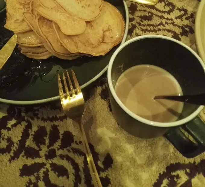 The image shows a plate of pancakes with syrup and a cup of coffee sitting on a table. A fork is also present on the table next to the plate.