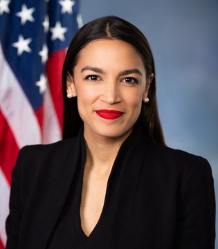 An official portrait shows U.S. Representative Alexandria Ocasio-Cortez (AOC) in a black blazer, standing before an American flag.