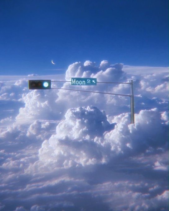 A surreal sky scene featuring fluffy clouds with a crescent moon and a street sign reading 'Moon St' with an arrow.