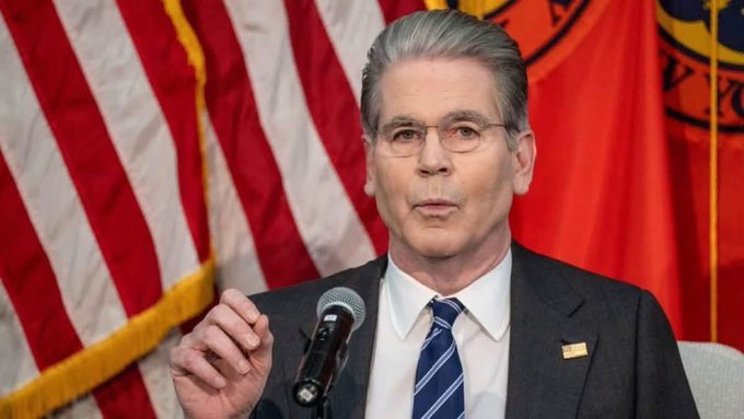 A man in a suit and tie speaks at a microphone with an American flag and a red flag in the background, consistent with an official Treasury appearance. The image ties to the post's claim about Treasury Secretary Scott Bessent advancing the CLARITY Act for a Senate vote, a development highlighted as bullish for $XRP.