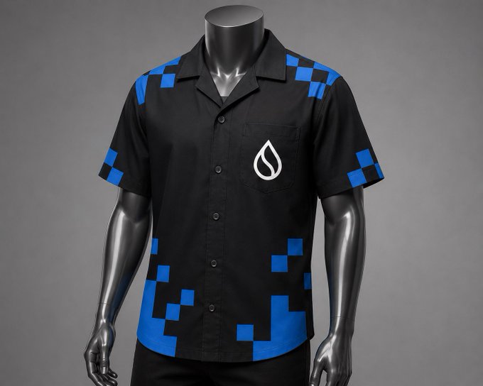 A black and blue pixel-patterned short-sleeve button-up shirt displayed on a mannequin, featuring a white teardrop-shaped logo on the chest pocket. The shirt's bold, tech-inspired design with digital mosaic accents complements the post's announcement of Sui Network's new high-speed prediction market product, Predict, reflecting the blockchain's modern, cutting-edge aesthetic.